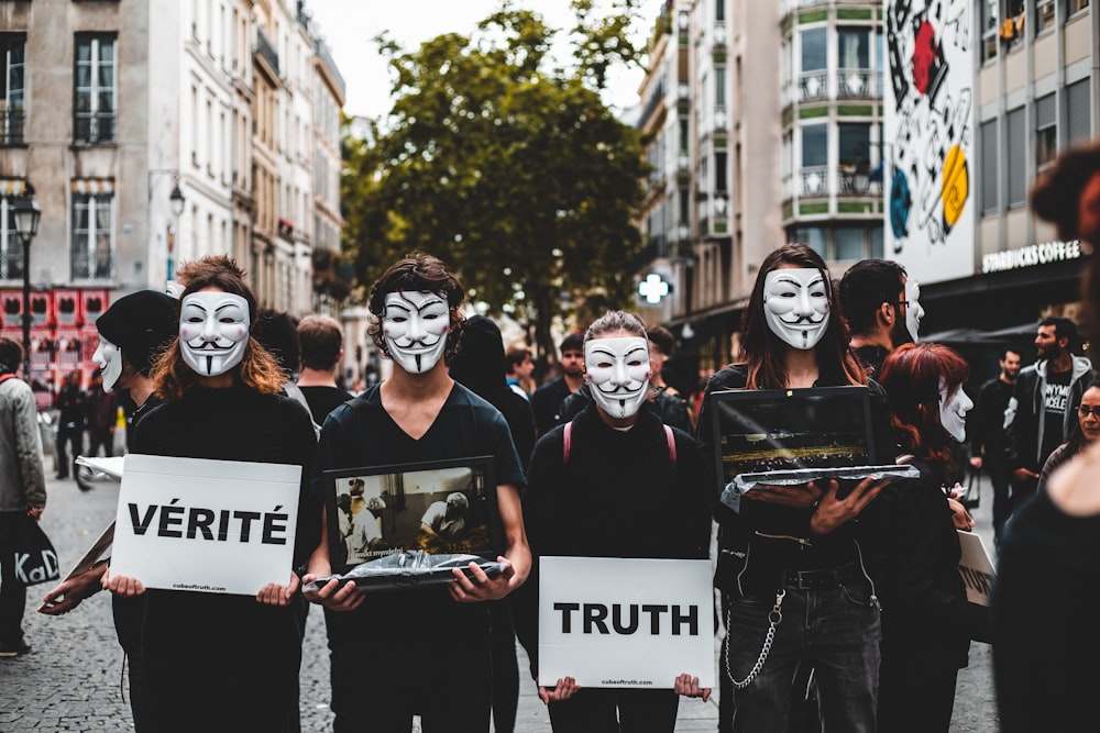 four people wearing Guy Fawkes masks