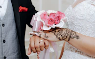 A candid shot of the bride's henna-adorned hands holding a delicate bouquet.
