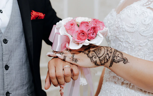 Close-up of intricate henna designs on a bride’s hands as she holds delicate ivory roses