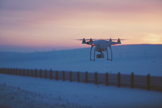A drone flying over a scenic landscape capturing cinematic footage at sunset.