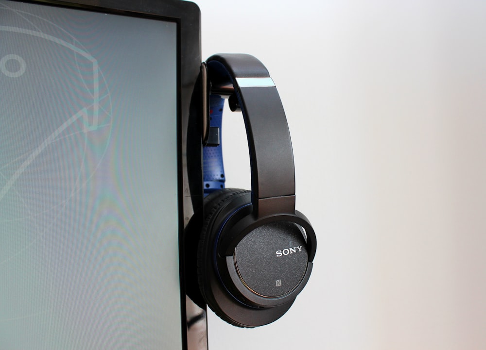 black Sony headphones hung beside computer monitor