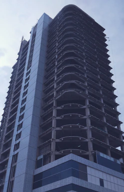 Architect reviewing blueprints on a modern building site with concrete and gold accents.