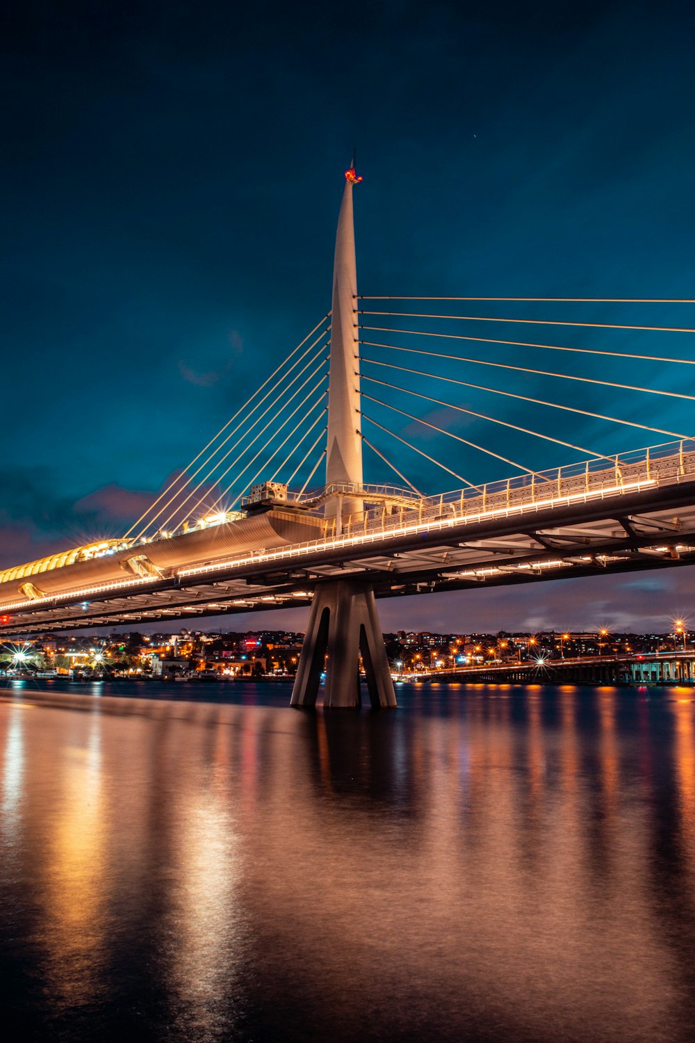 city with high-rise buildings showing self-anchored suspension bridge during night time