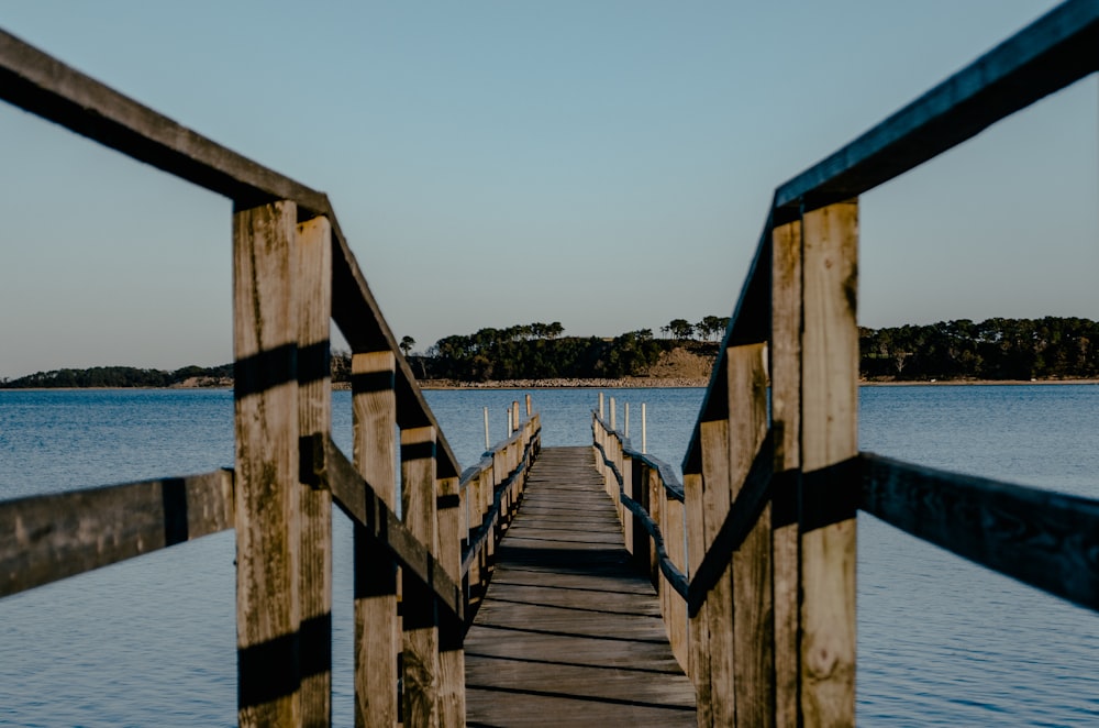 a wooden dock with water and trees in the background
