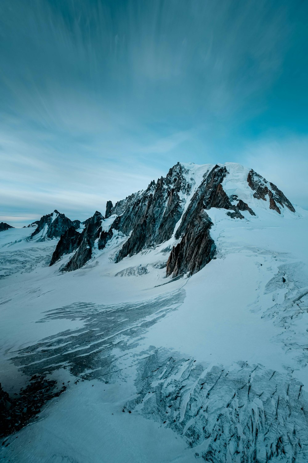 a mountain covered in snow under a cloudy sky