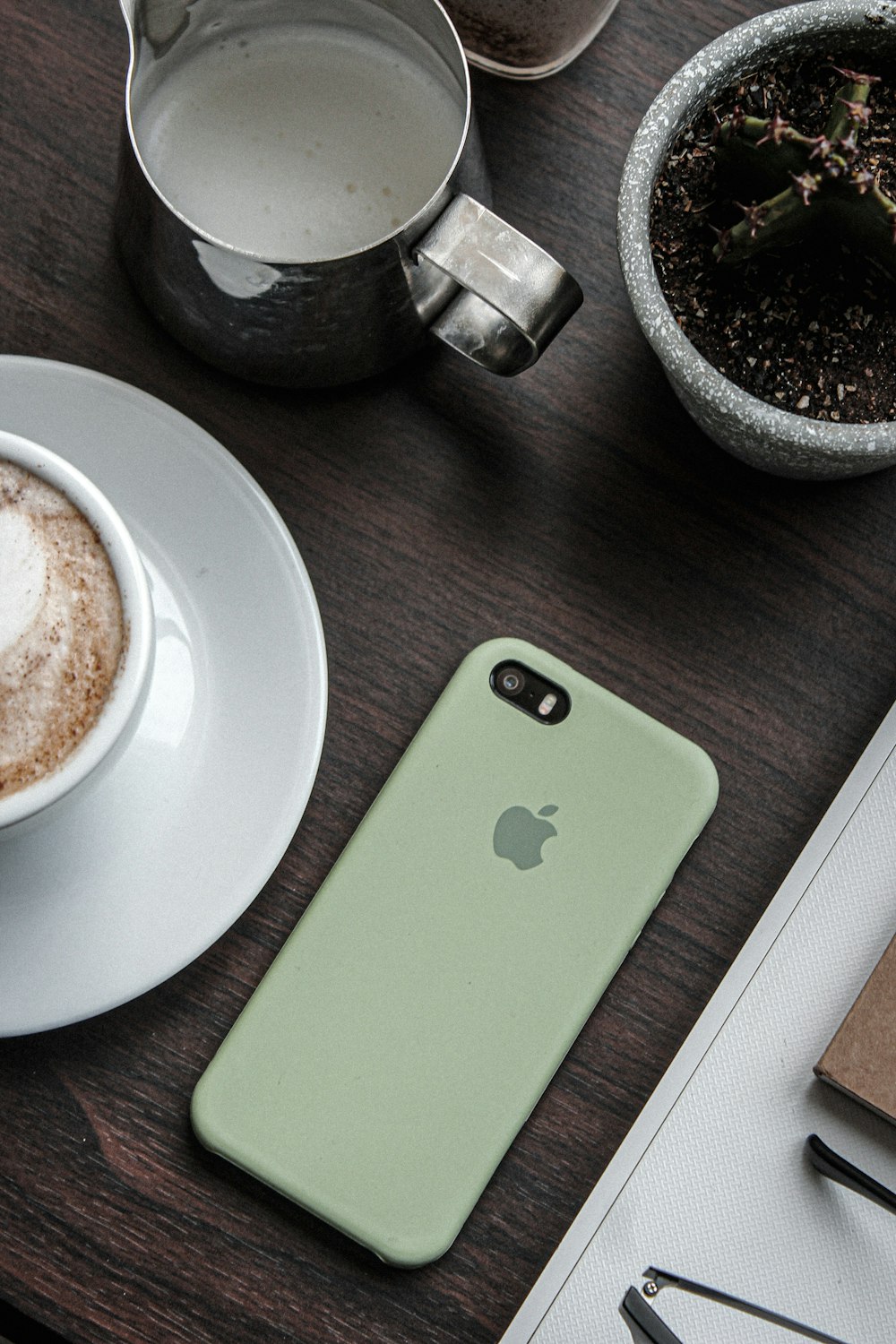 a cup of coffee next to a phone on a table