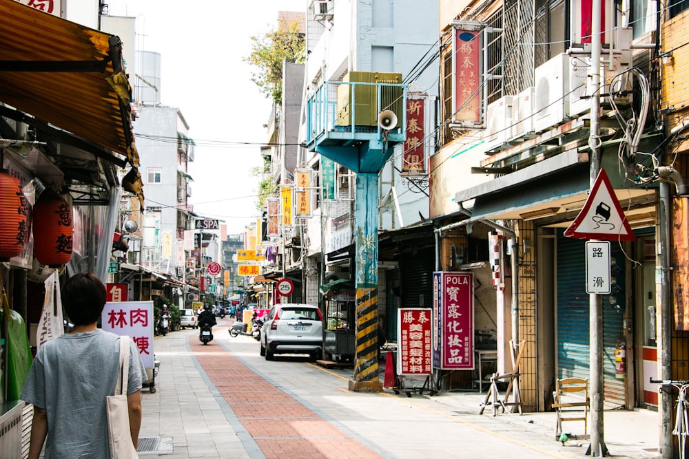 person wearing gray t-shirt walking on street during daytime