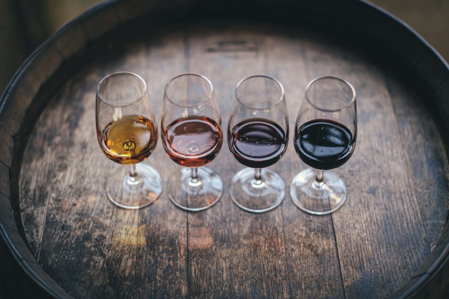 A flight of four wine glasses arranged on the head of an oak barrel