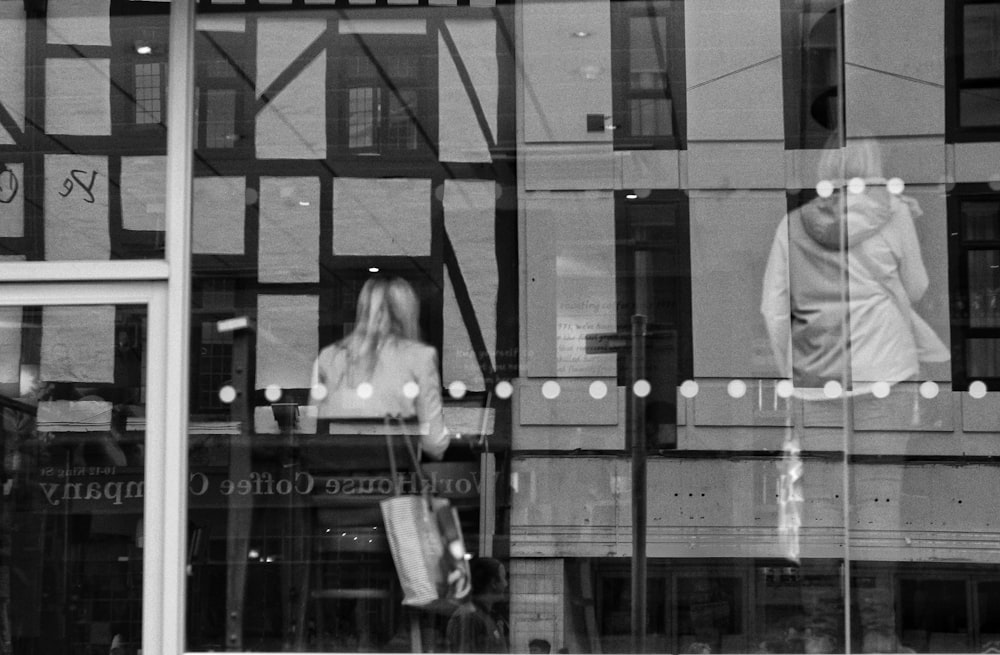 a black and white photo of a woman's reflection in a window