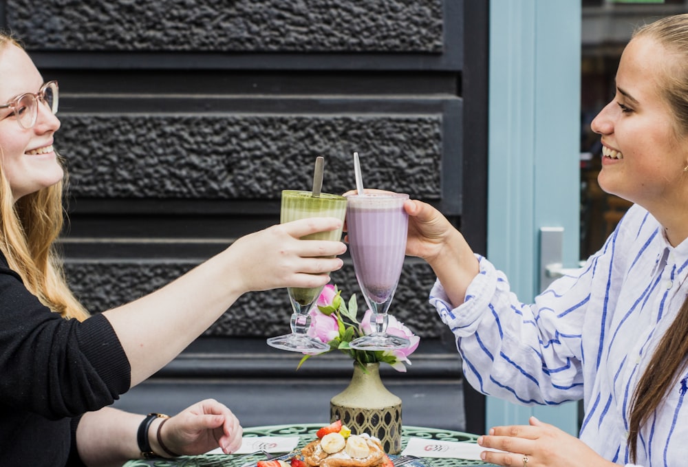 two women toasting drinks while smiling