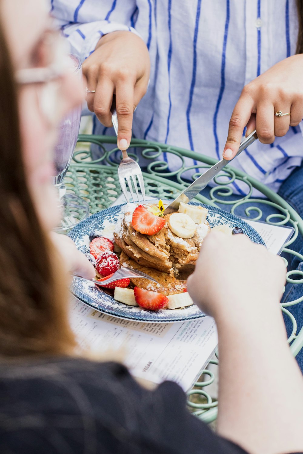 zwei Personen, die Utensilien auf Essen auf dem Teller verwenden