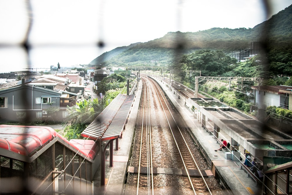 man sitting on waiting shed near train rail