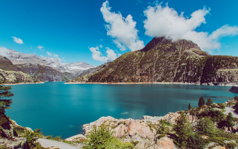 Montanha com vista para o lago sob o céu azul e branco durante o dia