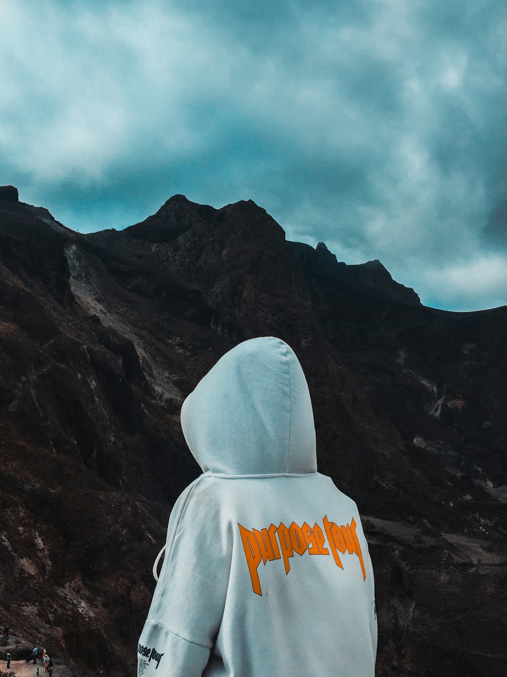 Person mit Kapuzenpullover mit Blick auf den Berg