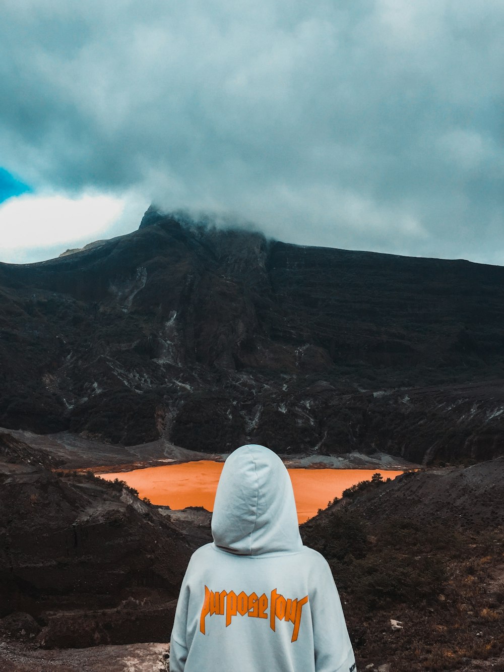 person wearing hoodie facing body of water