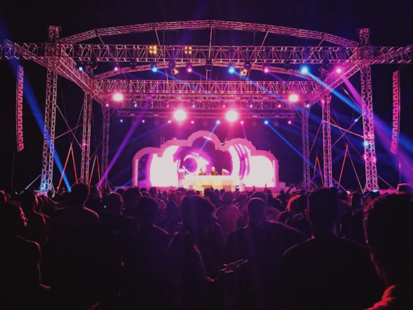 A lively event scene with a well-organized stage, vibrant lighting, and an engaged audience enjoying a concert.