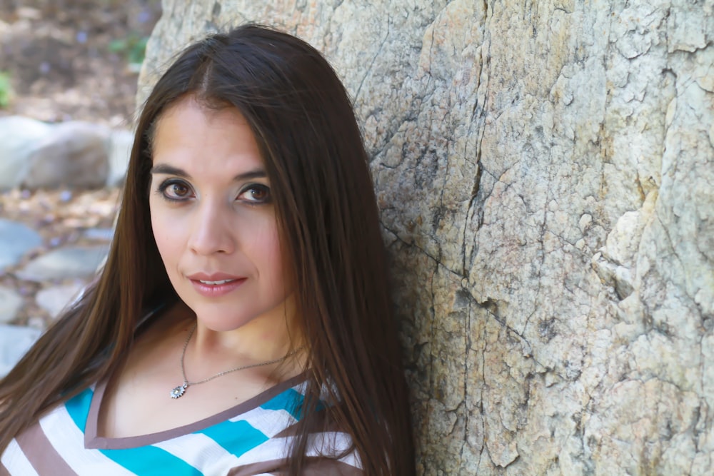 woman smiling and leaning on rocky wall