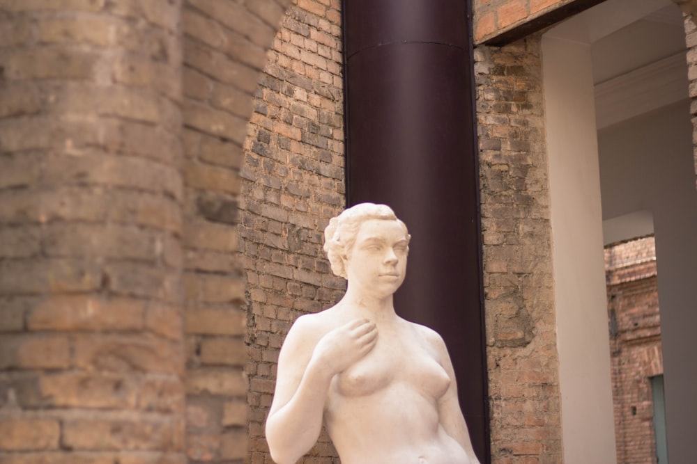 a statue of a naked woman in front of a brick building