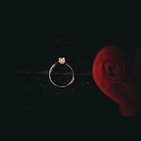 Close-up of a delicate rose gold ring with a single diamond on a soft beige fabric.