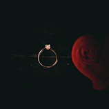 Close-up of a delicate rose gold ring with a sparkling diamond centerpiece against a softly blurred white background.