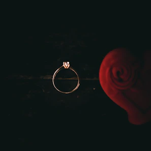 Close-up of a delicate rose gold ring with a sparkling diamond centerpiece against a softly blurred white background.