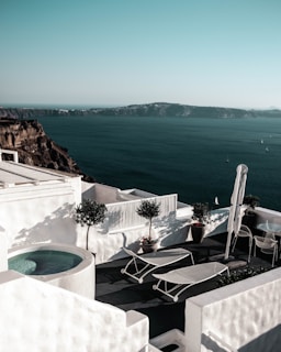 Elegant villa terrace overlooking a calm ocean under a soft grey-blue sky.