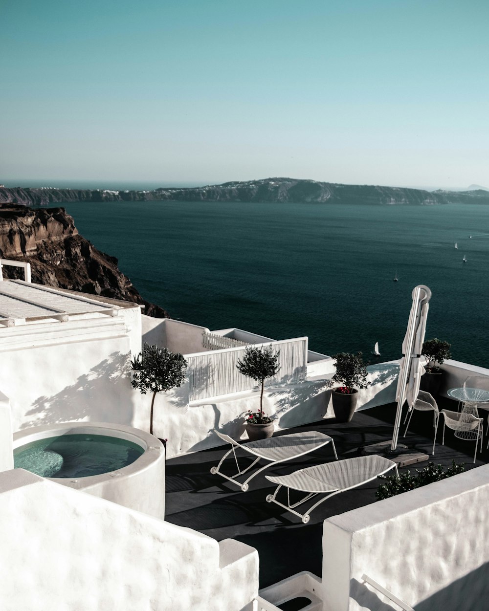 parasol, bistro set, plants, and lounge chairs on roof of building on island during day