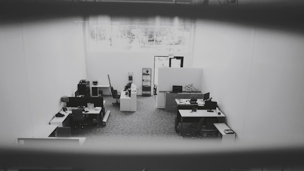 A janitor cleaning an office space with large windows and organized desks.