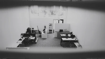 Close-up of a cleaner carefully wiping a desk with a microfiber cloth in a bright office space.