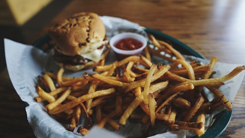 A vibrant shot of crispy golden fries served alongside a perfectly stacked smash burger.