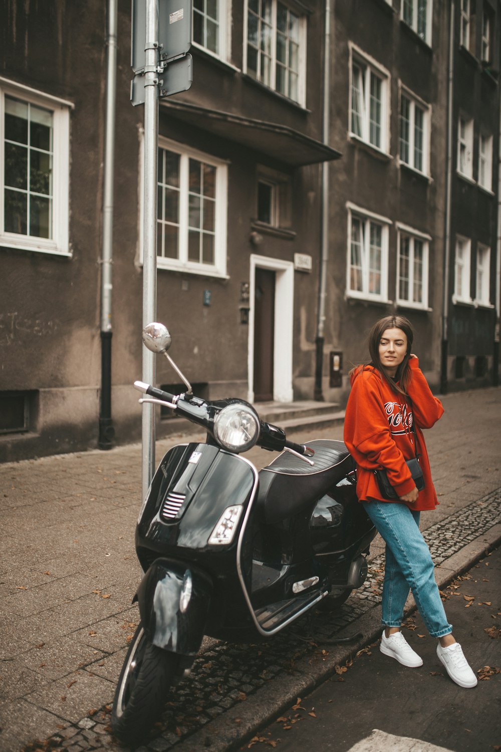 woman wearing orange pullover hoodie leaning on motorcycle