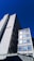 A tall, modern office building with multiple windows against a clear blue sky. The structure has clean lines and a minimalist design, with a sign that reads 'SPACES.' on the side. The building appears to be made of concrete or a similar material.