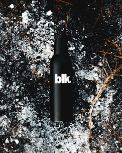 Dramatic shot of Divorox Ultra Obsidian Berry can surrounded by splashes of deep purple liquid on a near-black backdrop.