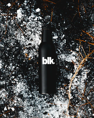 Dramatic shot of Divorox Ultra Obsidian Berry can surrounded by splashes of deep purple liquid on a near-black backdrop.