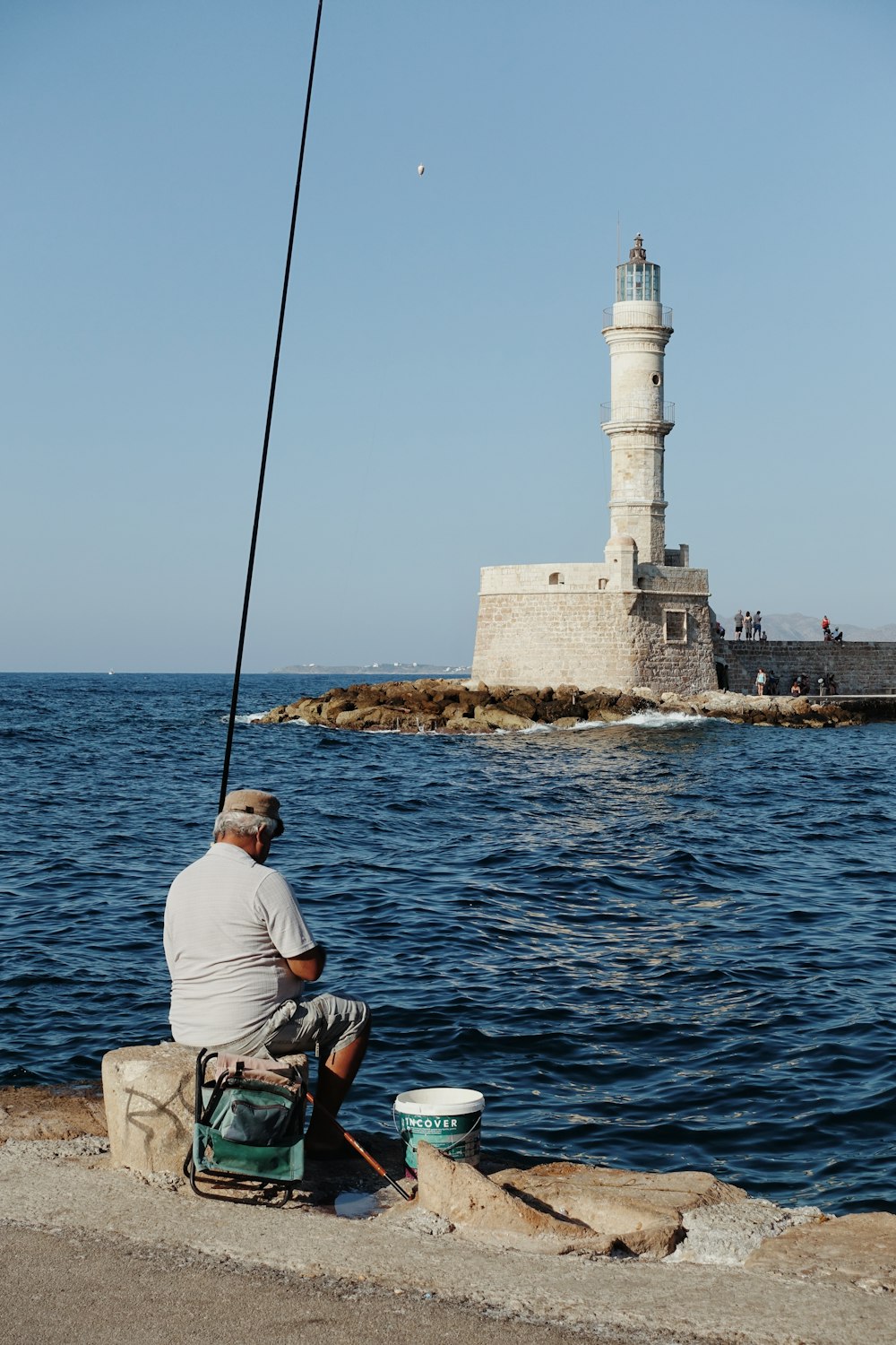 white stone lighthouse and a man fishing