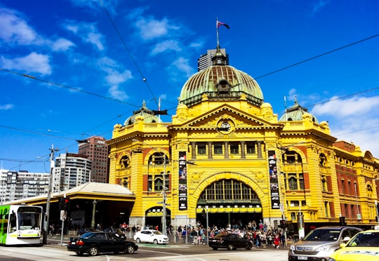 people exiting yellow building during daytime in Flinders Street railway station Australia