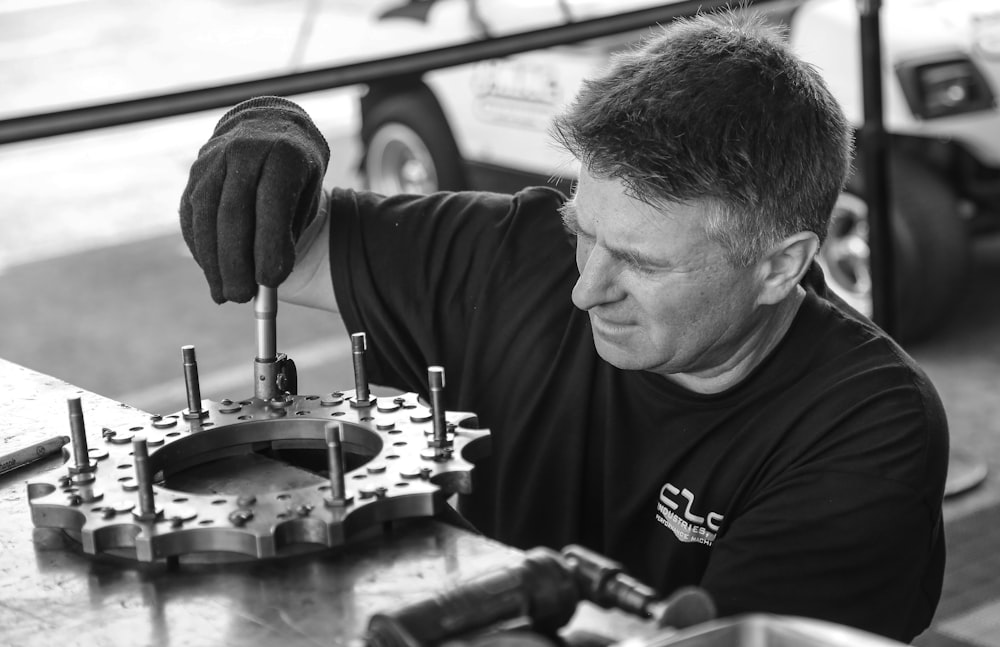 grayscale photo of man fixing gear