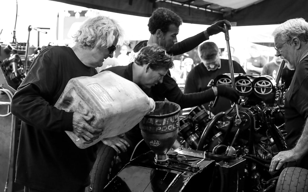 men pouring oil on vehicle