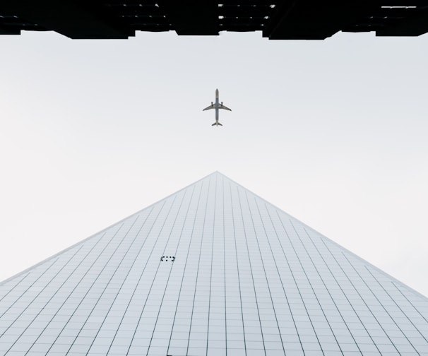 photo of white airplane midair and city building wormseye photography