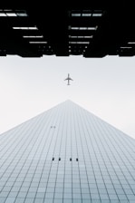 photo of white airplane midair and city building wormseye photography