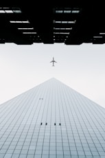 photo of white airplane midair and city building wormseye photography