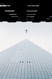 photo of white airplane midair and city building wormseye photography