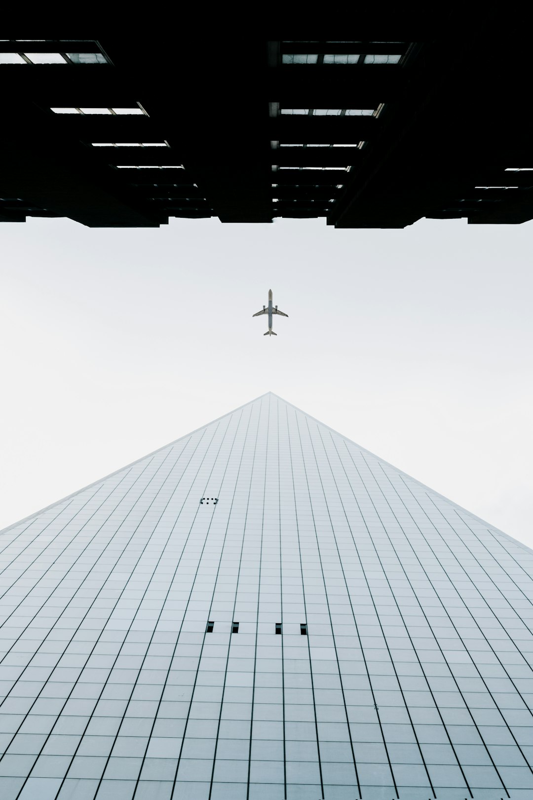 photo of white airplane midair and city building wormseye photography