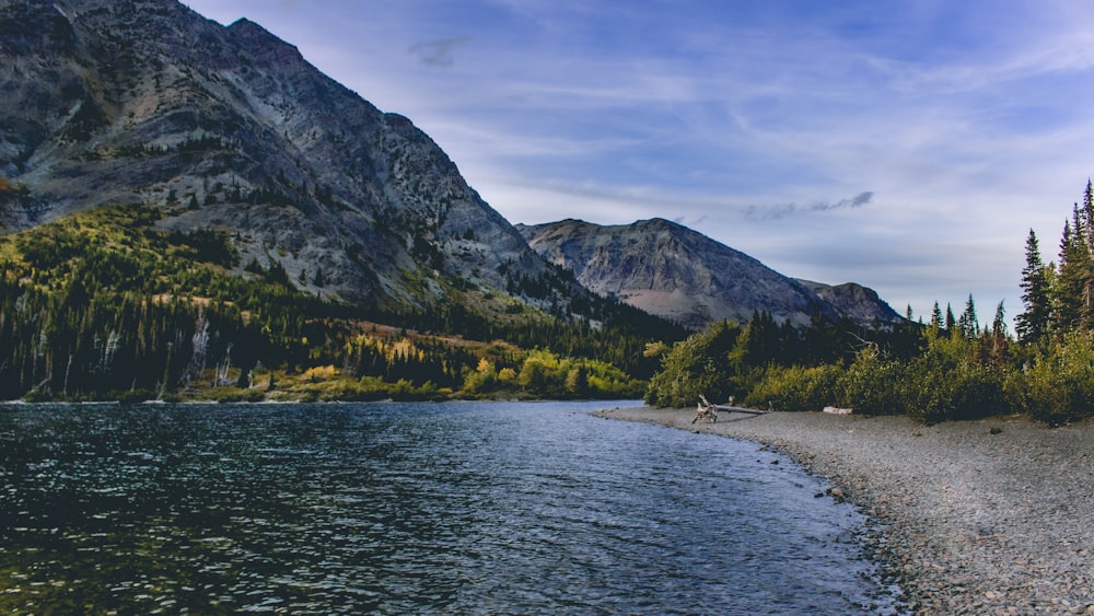 body of water near black and green mountains at daytime