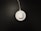 A white wireless charging pad with a pair of white earbuds in a case is situated on a dark surface. The charging pad is connected to a cable that extends out of the top of the image.