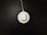 A white wireless charging pad with a pair of white earbuds in a case is situated on a dark surface. The charging pad is connected to a cable that extends out of the top of the image.
