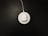 A white wireless charging pad with a pair of white earbuds in a case is situated on a dark surface. The charging pad is connected to a cable that extends out of the top of the image.