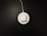 A white wireless charging pad with a pair of white earbuds in a case is situated on a dark surface. The charging pad is connected to a cable that extends out of the top of the image.