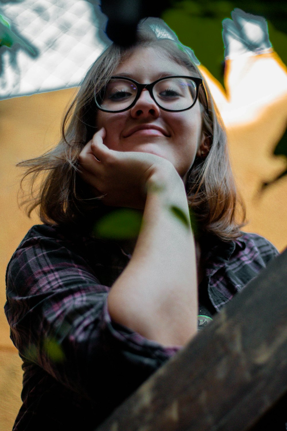 a woman wearing glasses leaning on a wooden bench