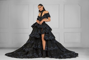 Model wearing a sleek, minimalist evening gown standing against a clean white backdrop.